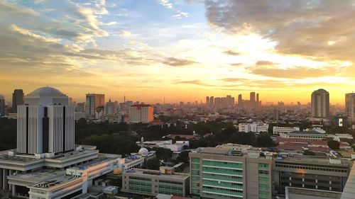 Modern buildings in city against sky during sunset