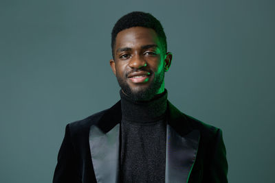Portrait of young man standing against gray background