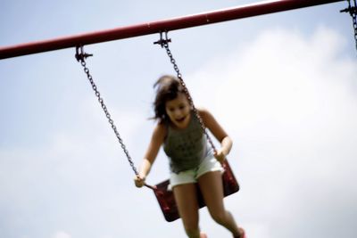 Girl playing on swing in playground