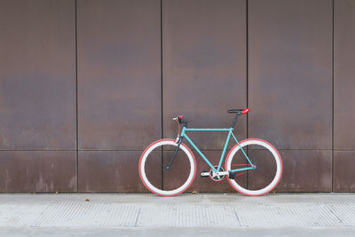 Bicycle on footpath against wall