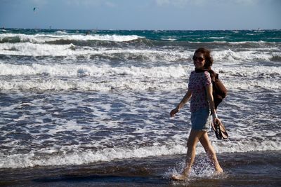 Full length of smiling young woman walking at beach