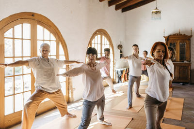 Multiracial friends practicing warrior position in yoga studio