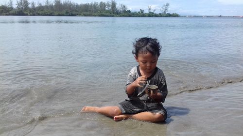 Boy sitting on lakeshore