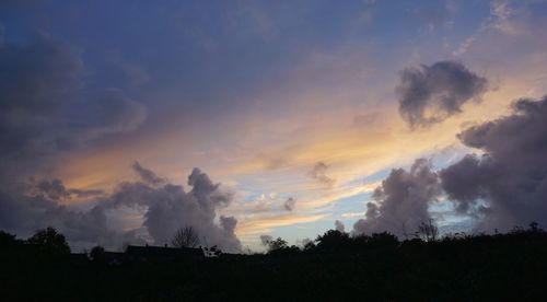 Low angle view of silhouette trees against dramatic sky