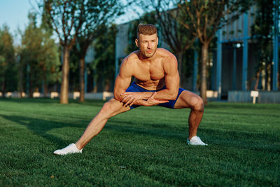 Portrait of shirtless man exercising on field