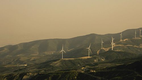 Scenic view of windmills on mountains against clear sky