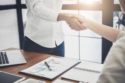 Close-up of businesswomen shaking hands in office