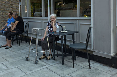 People sitting on chair at sidewalk