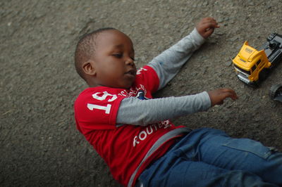 Boy lying down by toy car