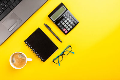 High angle view of yellow and coffee cup on table