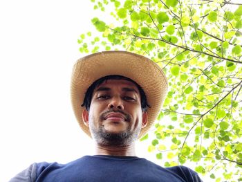 Portrait of young man wearing hat against trees