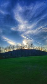 Scenic view of grassy field against cloudy sky