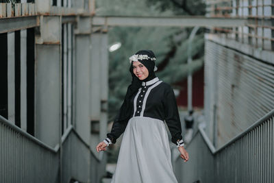 Portrait of smiling young woman standing against building