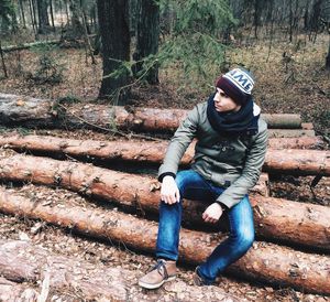 Full length of young man sitting in forest