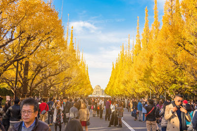 Group of people in autumn leaves against sky