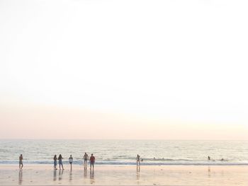 People on beach against clear sky