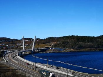 Road by bridge against clear blue sky