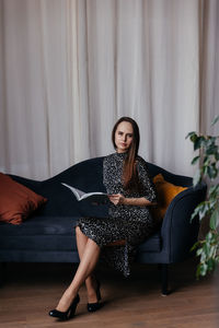 Young woman sitting on bed at home