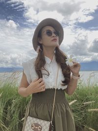 Young woman wearing sunglasses standing on land against sky
