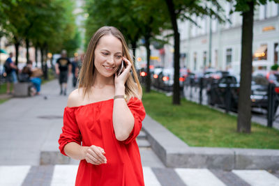 Caucasian woman with smartphone, standing against street blurred street