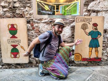 Portrait of young man standing against graffiti wall