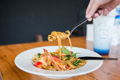 Midsection of person having food in plate on table