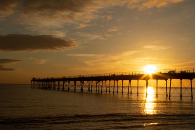 Silhouette pier over sea against sky during sunset