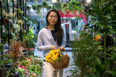 Portrait of smiling woman standing against plants