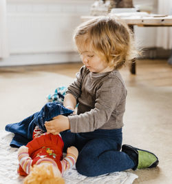 Cute baby girl playing with doll at home