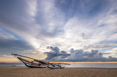 Boat moored on beach against sky