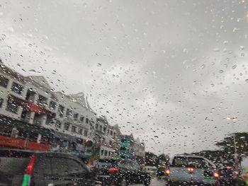 Cars on road seen through wet window in rainy season