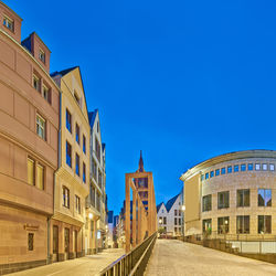 Street amidst buildings against clear blue sky