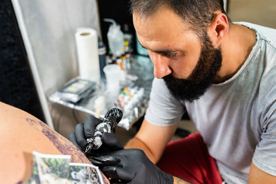 Man tattooing on customer back