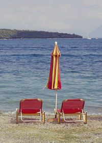 Chairs on beach against sky