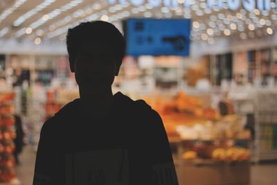 Portrait of man standing in illuminated store at night