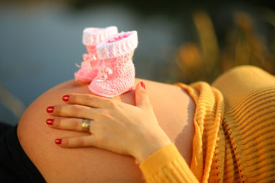 Close-up of pregnant woman with baby booties on abdomen