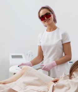 Young woman wearing sunglasses while sitting on bed at home
