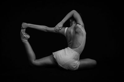 Midsection of woman dancing against black background