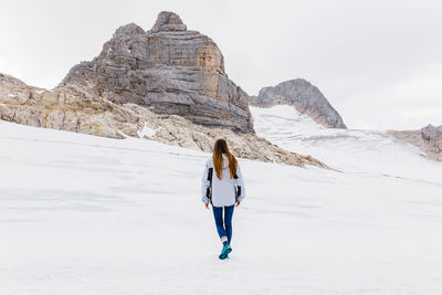 Young millennial girl enjoys the views of the alps standing on glacier