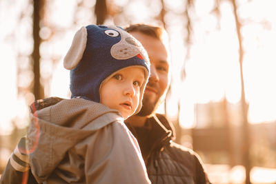 Portrait of father holding son outdoors in park in autumn