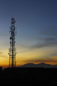 Silhouette of communications tower against sky during sunset