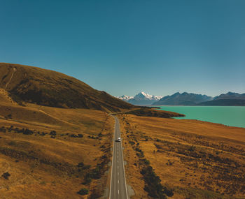 Panoramic view of road amidst mountains against clear blue sky