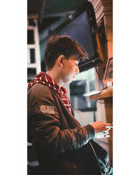 Side view of young man reading book