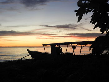 Silhouette boat on beach against sky during sunset