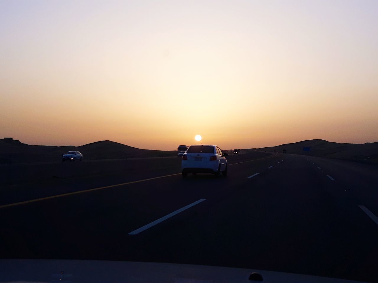 car, motor vehicle, transportation, mode of transportation, sky, sunset, land vehicle, road, no people, copy space, travel, nature, beauty in nature, scenics - nature, on the move, journey, clear sky, silhouette, orange color, non-urban scene, road trip