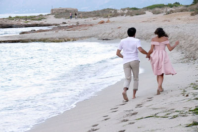 Rear view of couple walking on beach