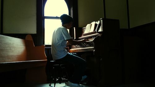 Side view of man playing piano