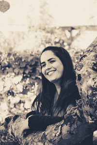 Smiling woman standing by branch