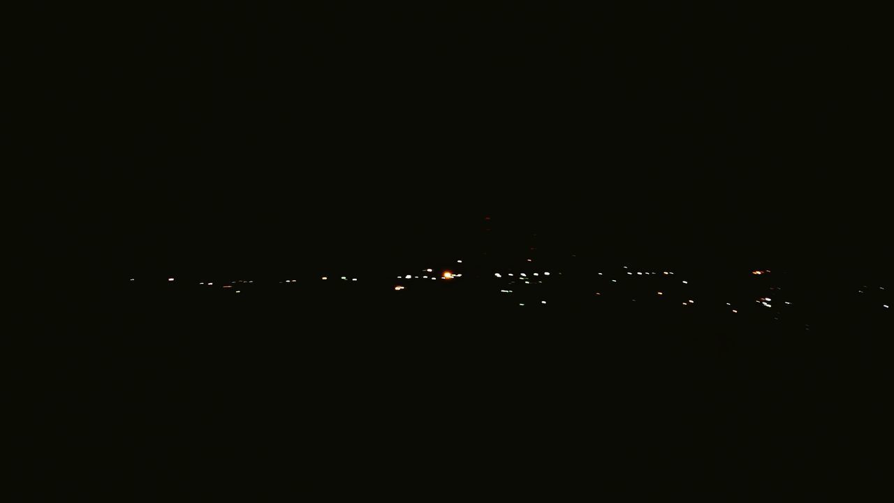 DISTANT VIEW OF ILLUMINATED CITY AGAINST SKY