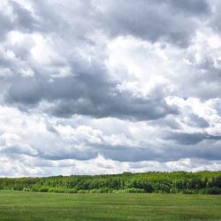 Scenic view of grassy field against cloudy sky